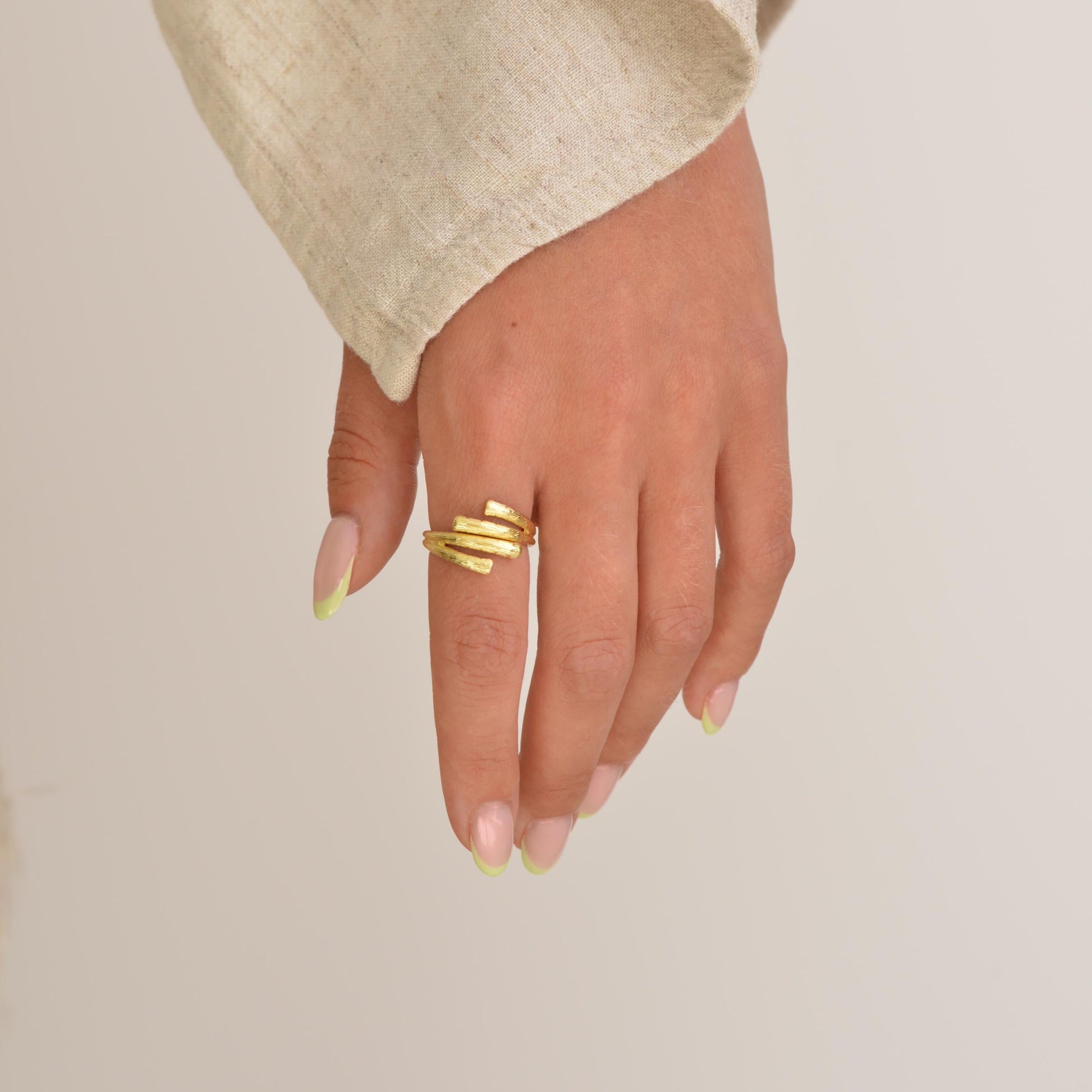 Hand wearing a gold ring on a plain background