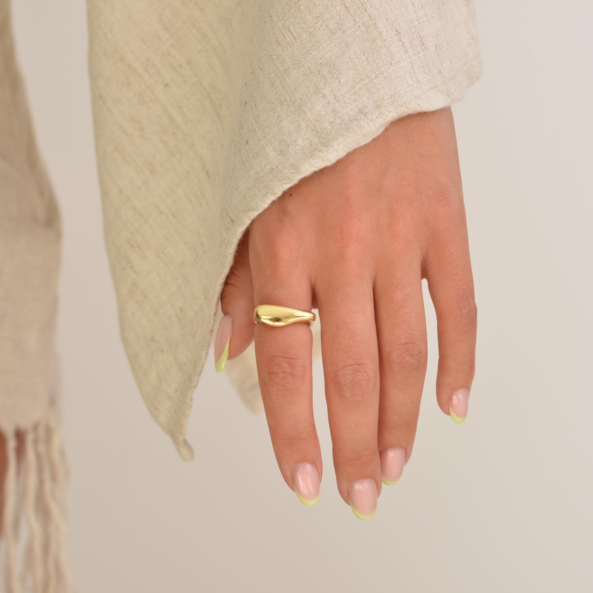 Hand wearing a gold ring with a plain background