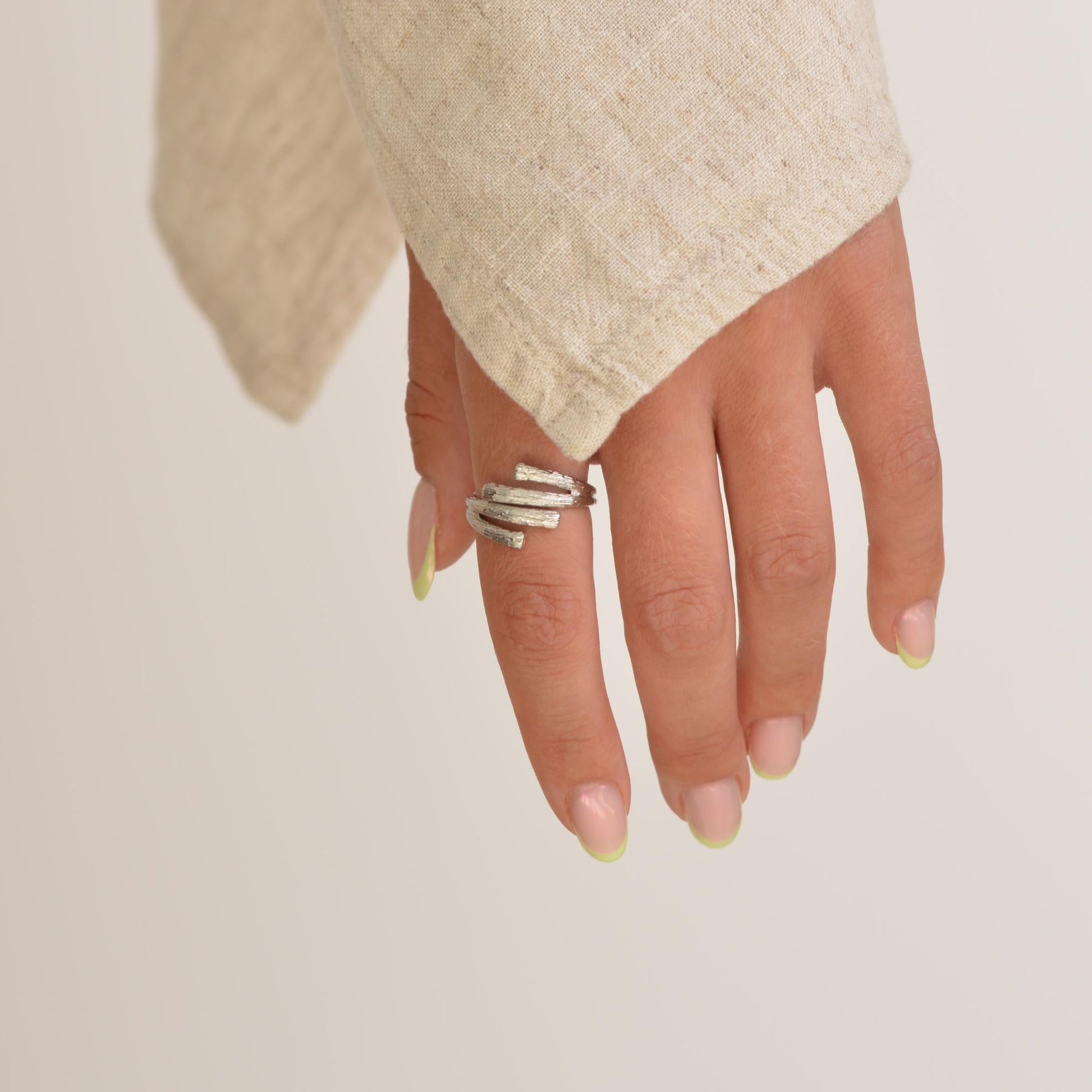 Hand wearing a silver ring on a plain background