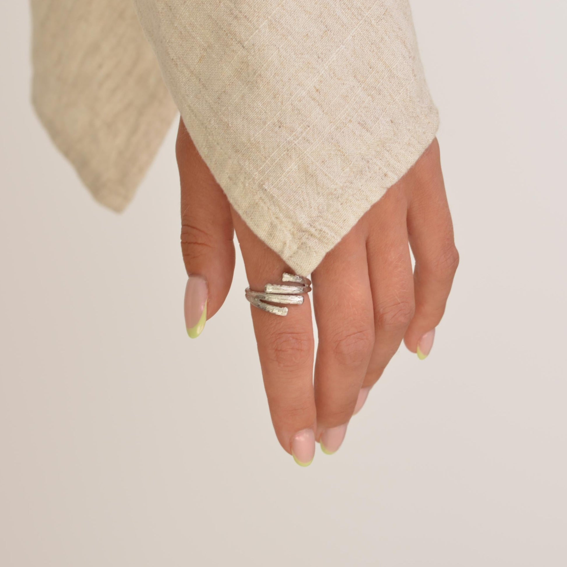 Hand wearing a silver ring on a plain background