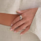Hand wearing a silver ring on a plain background