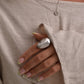 Close-up of a hand wearing a silver ring with a beige background