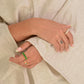 Close-up of hands wearing rings on beige fabric