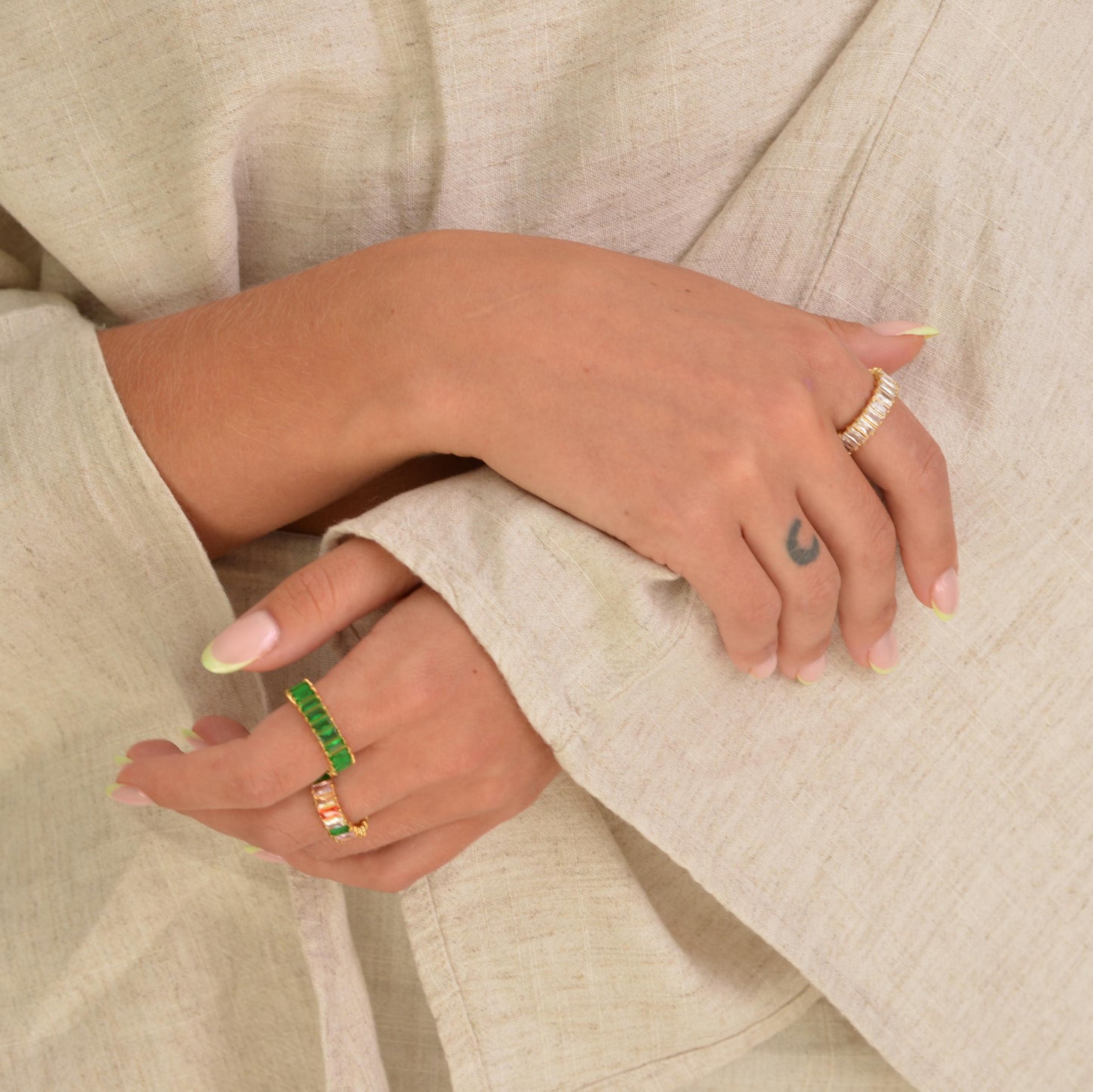 Close-up of hands wearing rings on beige fabric
