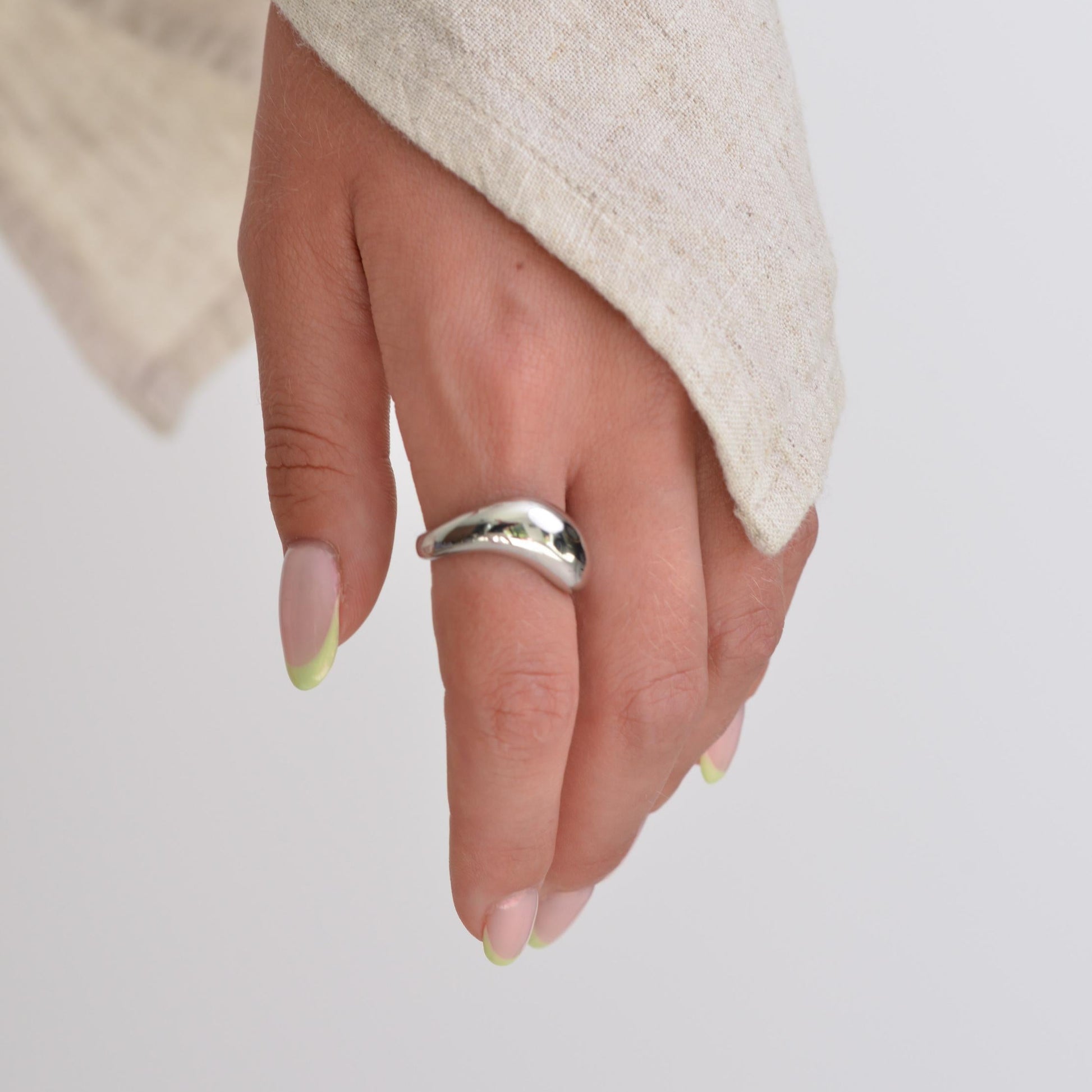 Hand wearing a silver ring on a plain background