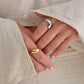Close-up of hands wearing gold and silver rings with beige fabric background