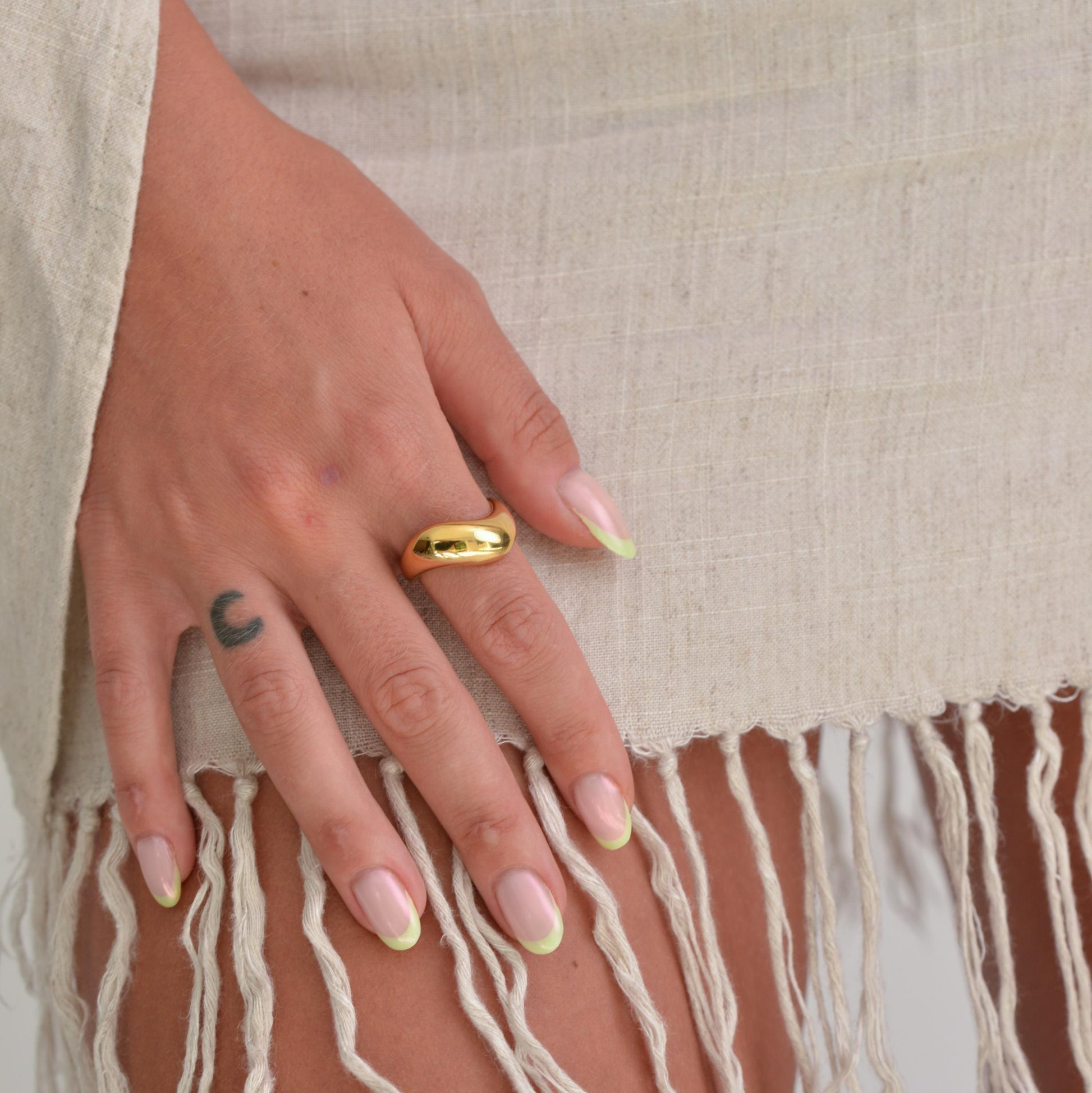 Hand with a gold ring on a textured beige fabric background