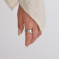 Hand wearing a silver ring on a plain background