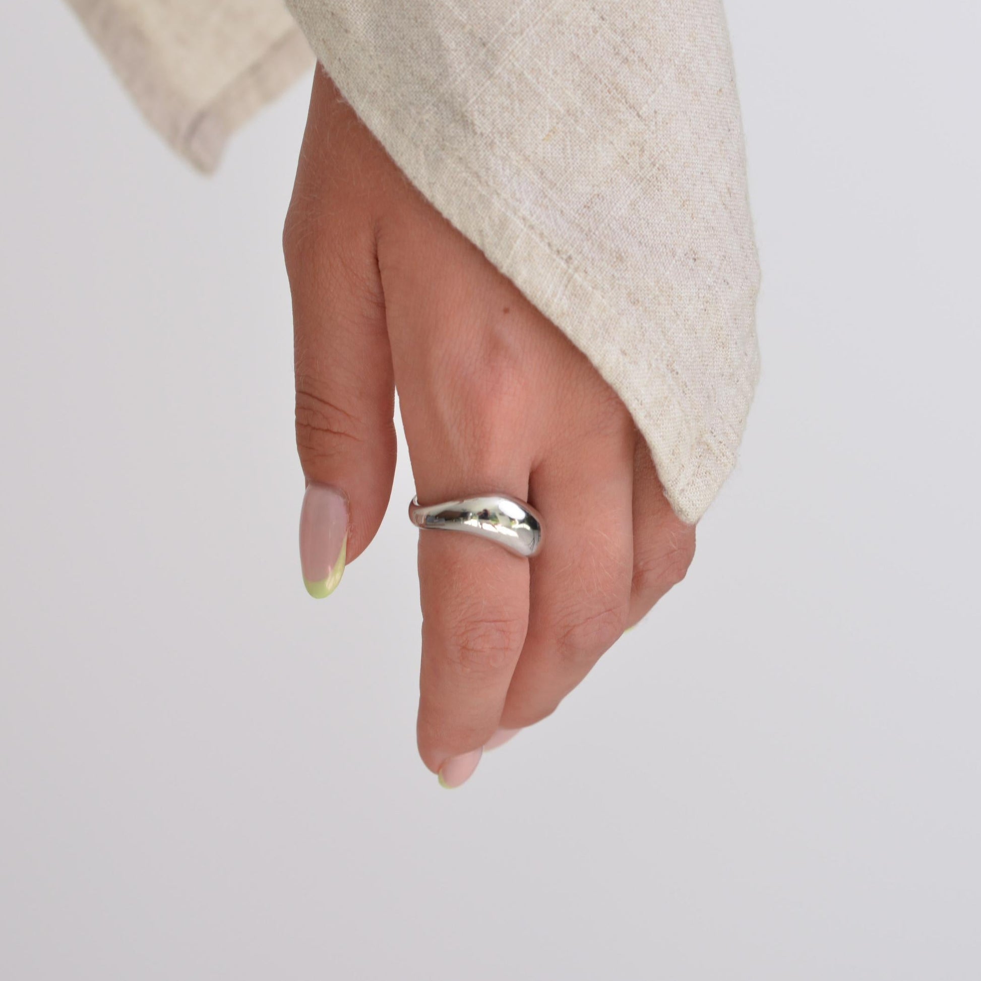 Hand wearing a silver ring on a plain background