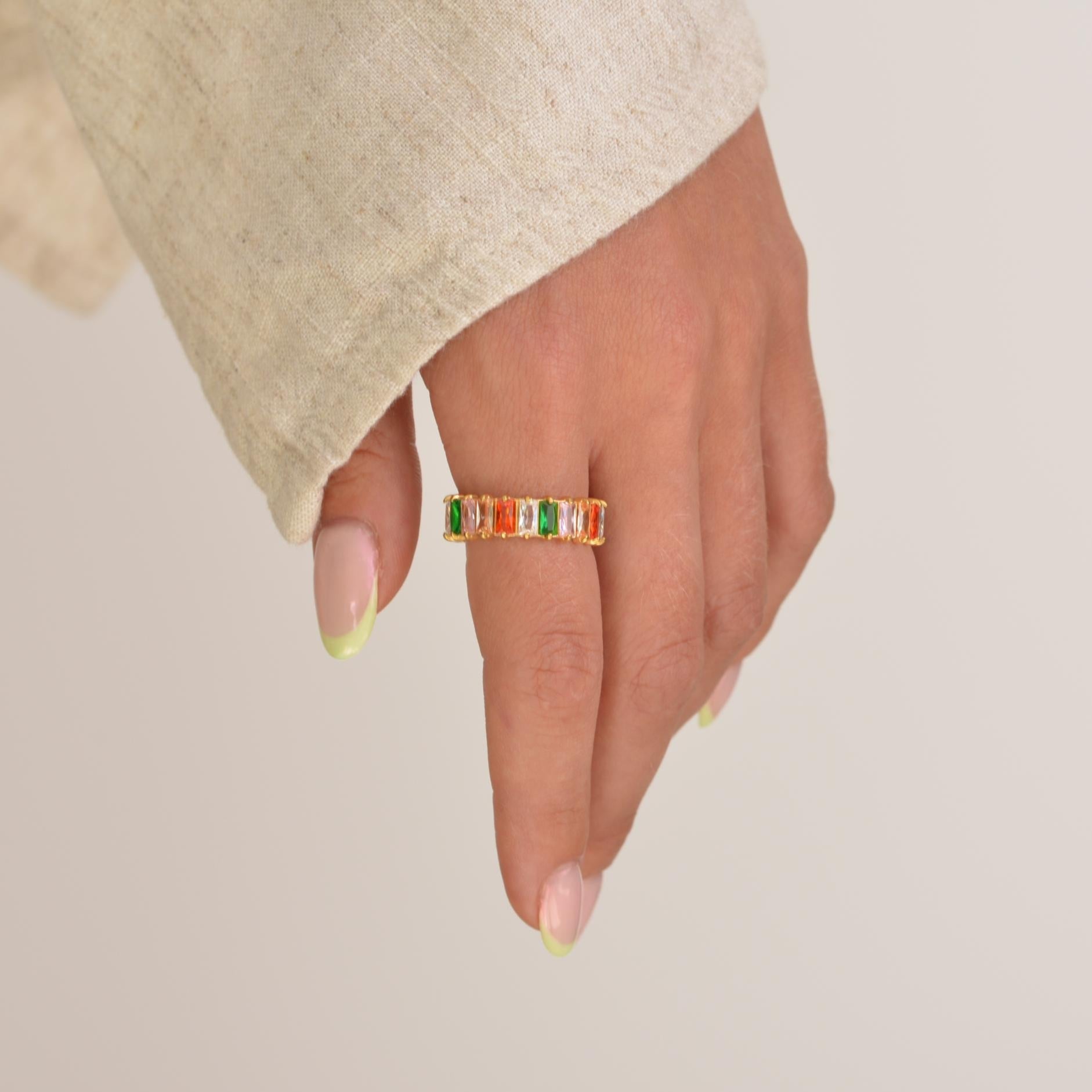 Hand wearing a colorful ring on a plain background