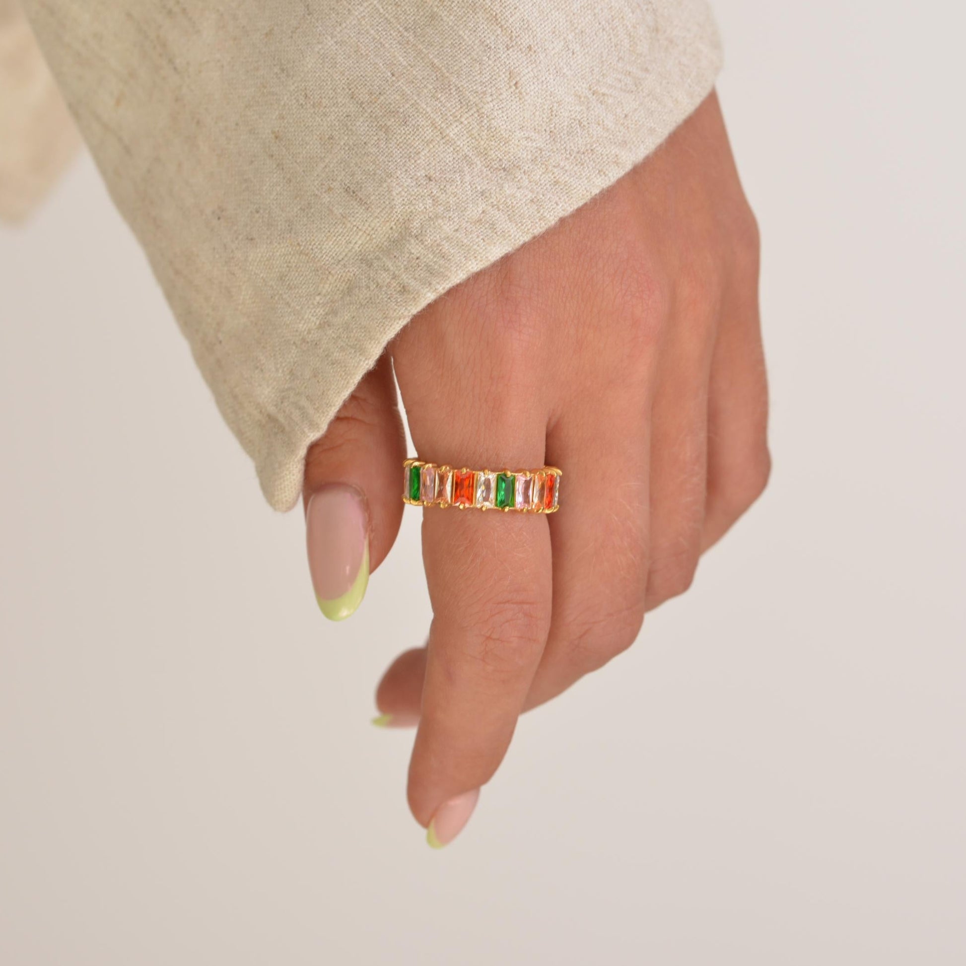 Hand wearing a colorful ring on a plain background