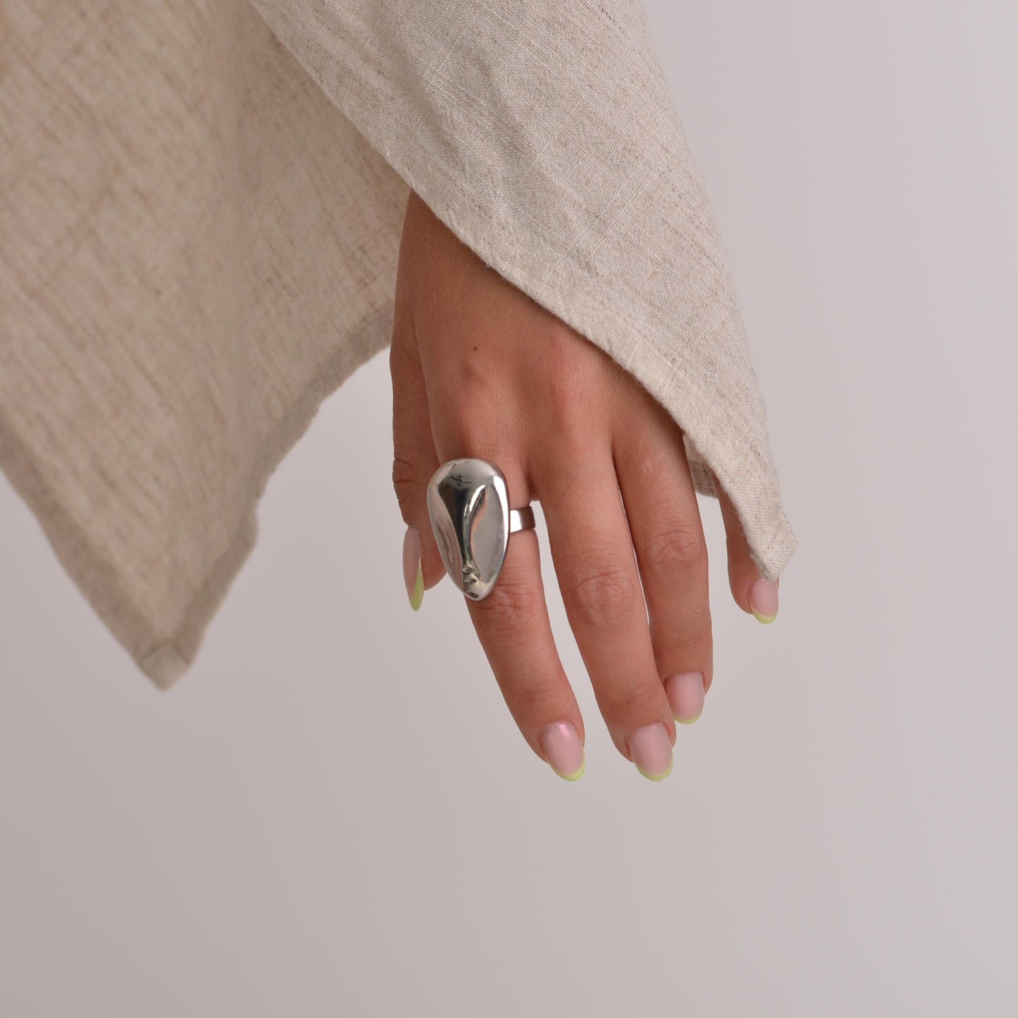 Hand wearing a silver ring with a neutral background