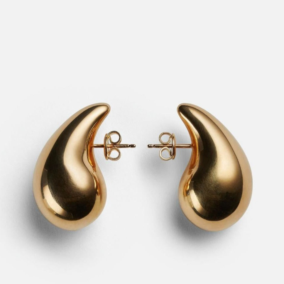 Pair of chunky gold teardrop stud earrings with butterfly backs on a light grey background
