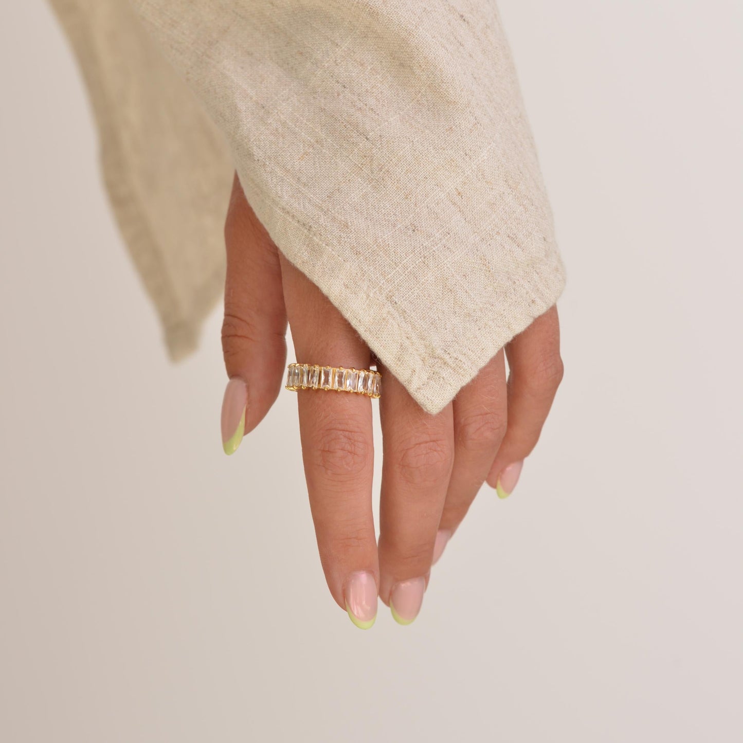 Hand wearing a gold ring on a plain background