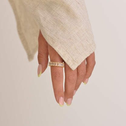 Hand wearing a gold ring on a plain background